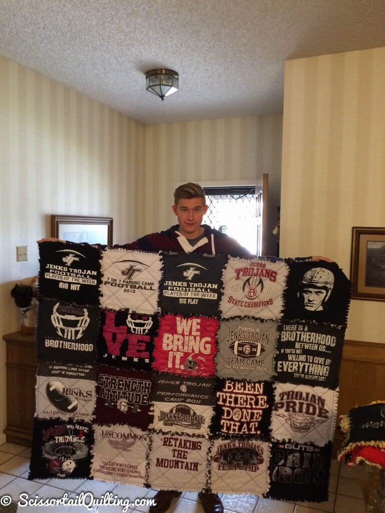 Young man holding a tshirt quilt in maroon and gray colors