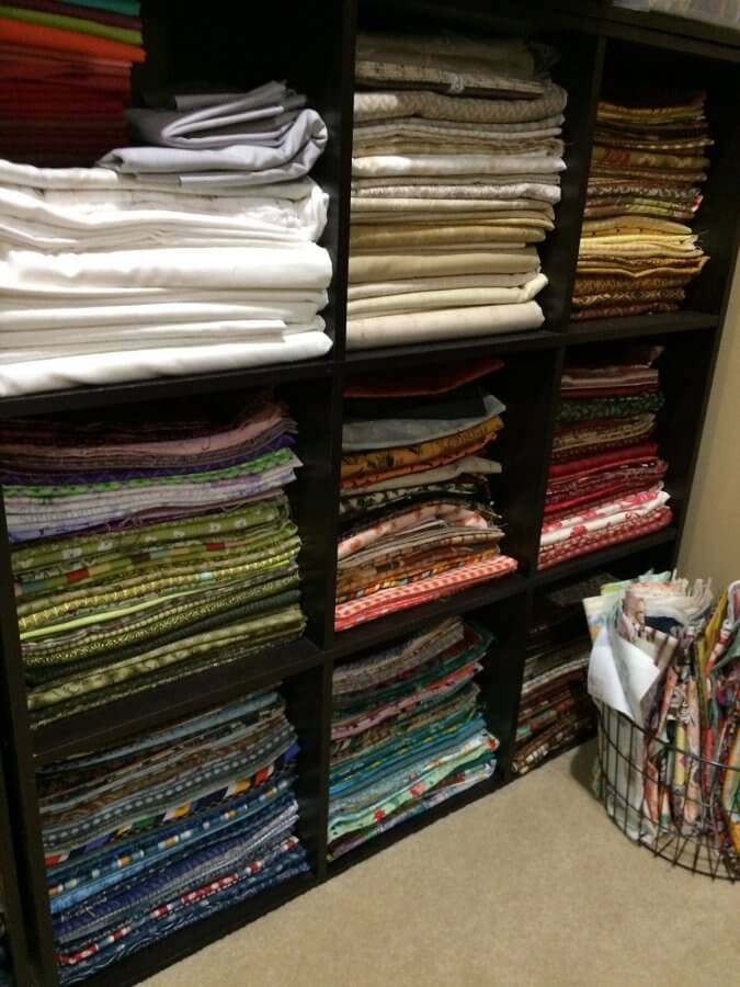 Photo showing shelves of fabric in nearly organized stacks