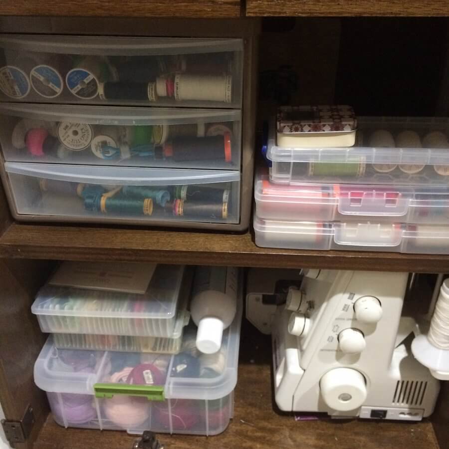 Photo of shelves in side a cabinet containing a serger and boxes of thread