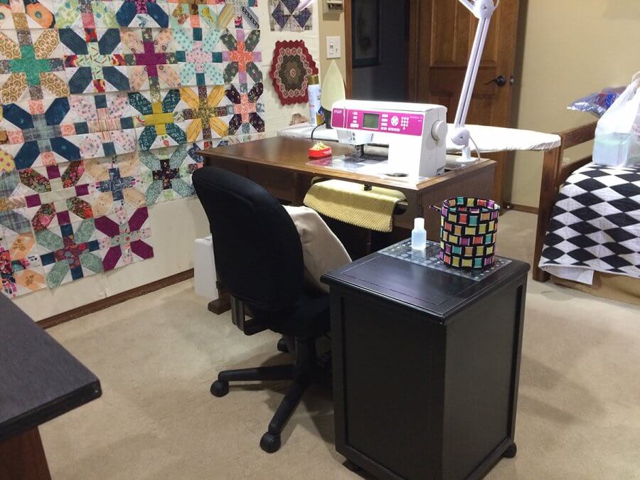 Photo of a sewing machine in a cabinet with a chair and side cabinet 