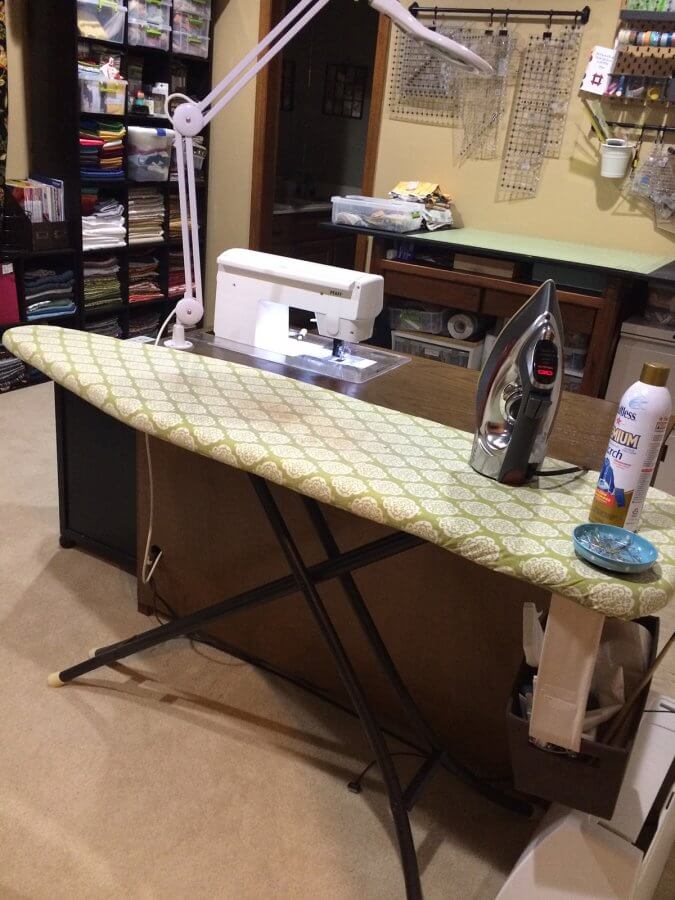 Photo of a room set up with sewing station and ironing board