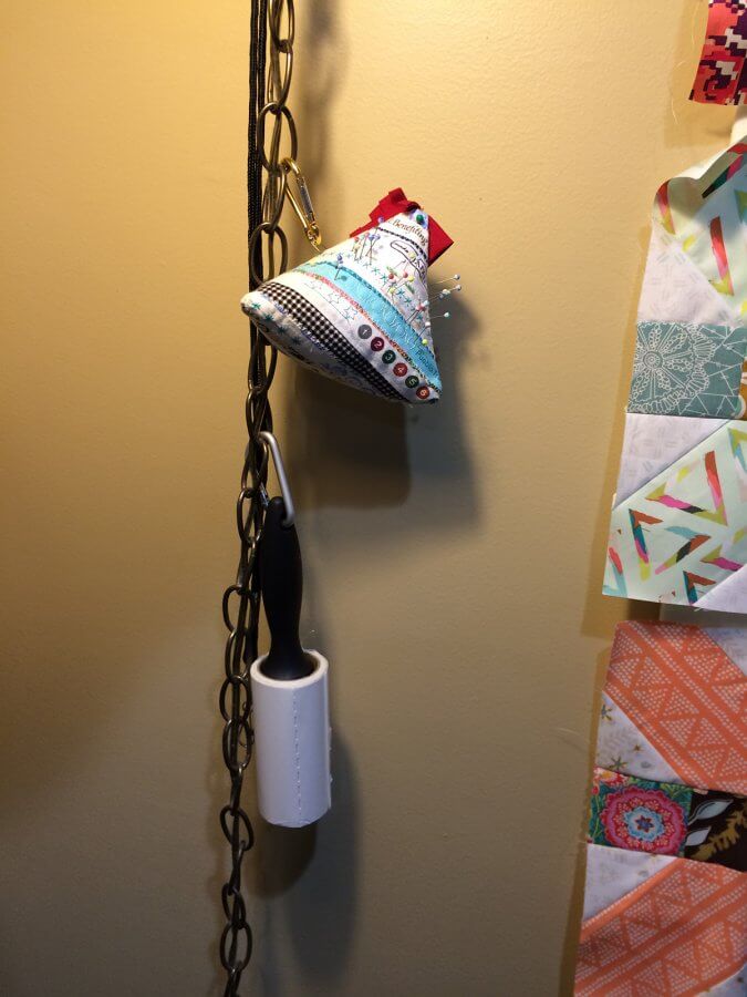 Photo of a chain from a hanging lamp with a pin cushion and lint roller hanging from it