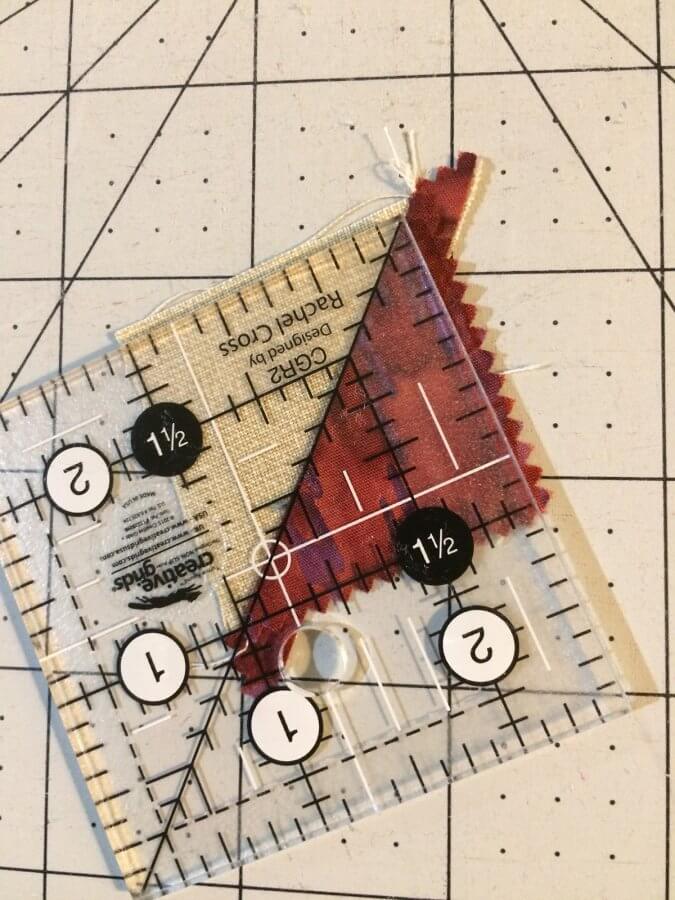 Photo of a clear acrylic ruler used to trim a Half Square Triangle made from a leftover Quick Corner