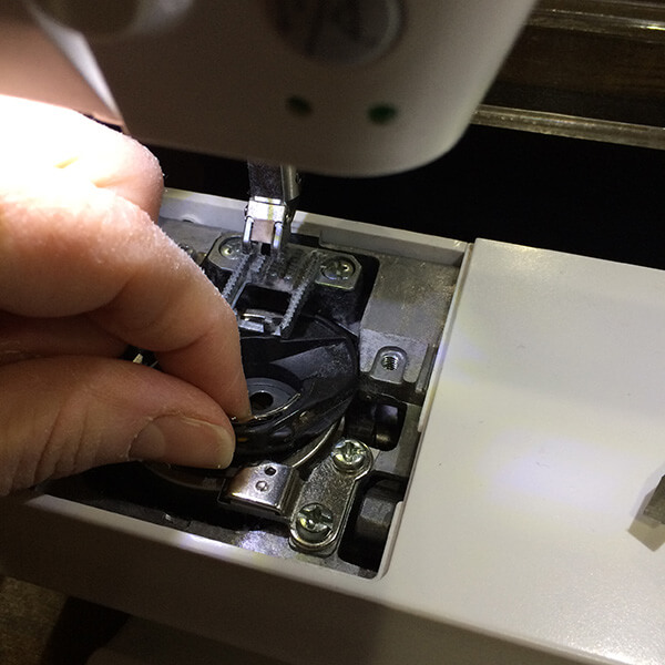 photo showing how to remove a bobbin from the bobbin case of a sewing machine