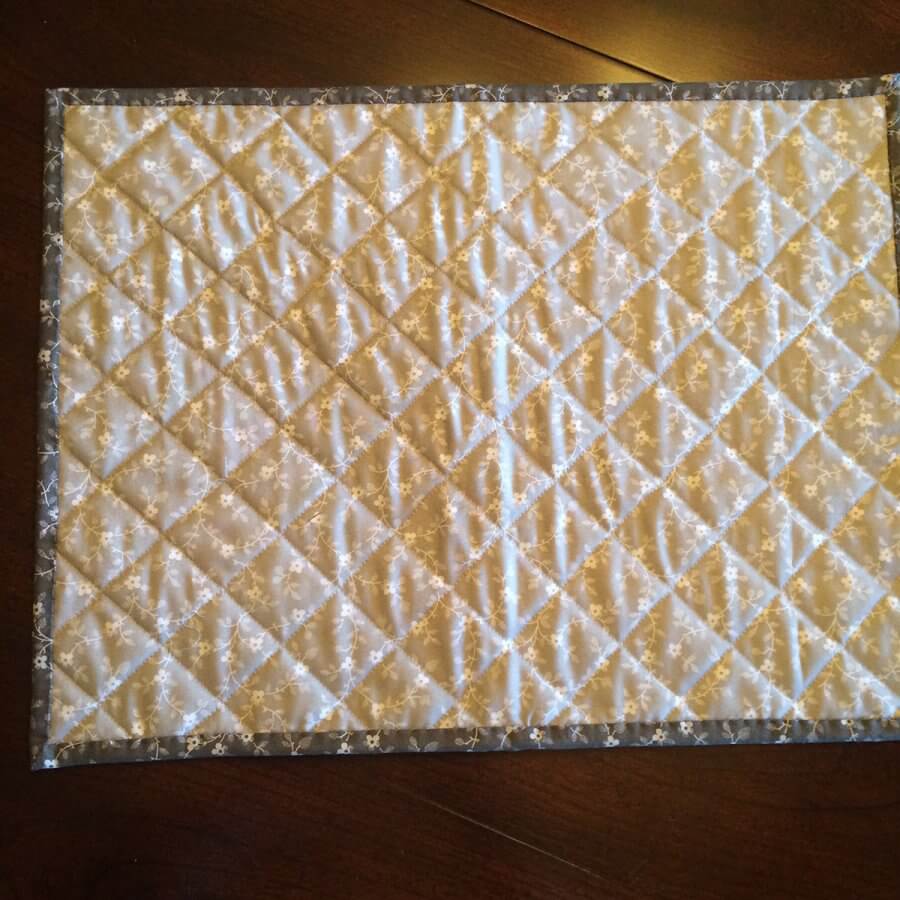 Photo of back side of tiny geese placemat, showing grid quilting lines