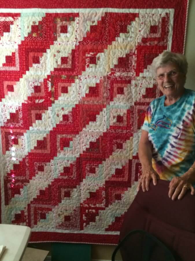 Picture of Emma infront of her red white and blue log cabin quilt
