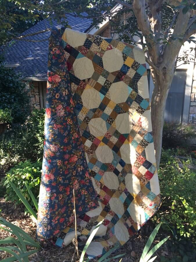 photo of 9-patch snowball quilt under tree swaying in wind