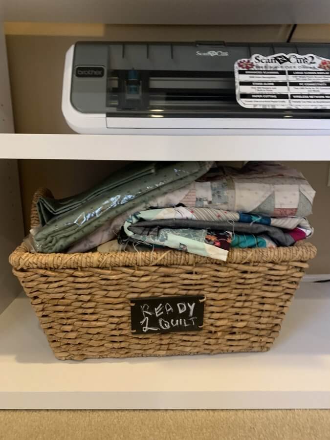 basket containing quilt tops with a tag that reads "Ready 2 Quilt"